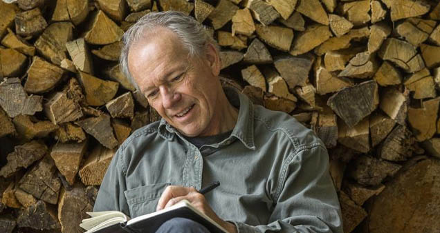 A man smiles while writing in a journal