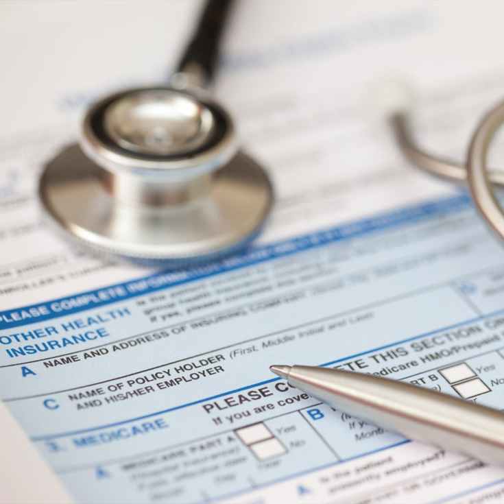 A closeup of documents, a pen and a stethoscope