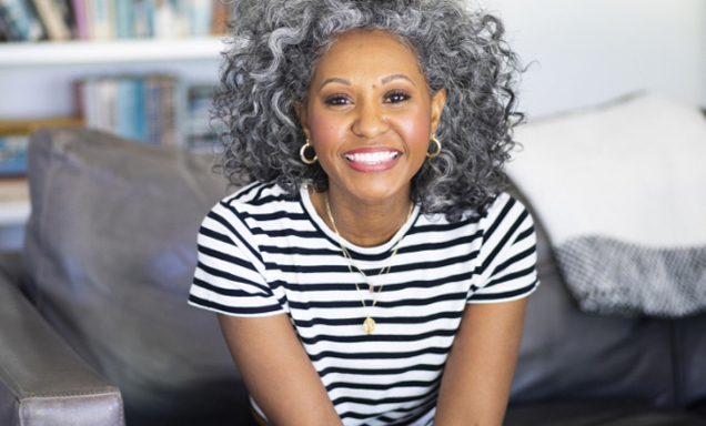 A happy woman sits in her living room.