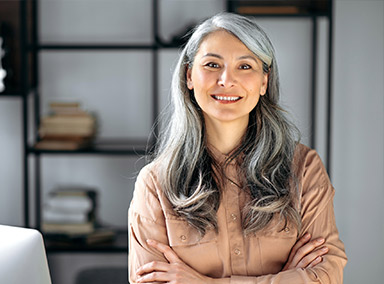 A woman smiles while in a park.