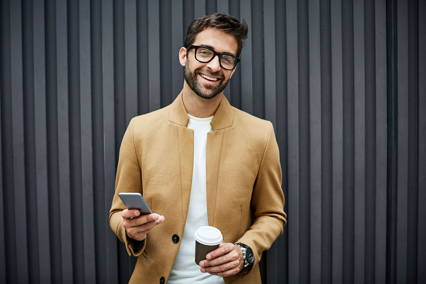 Man holding phone and a coffee