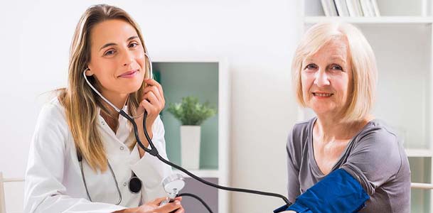 A doctor takes the blood pressure of her senior patient
