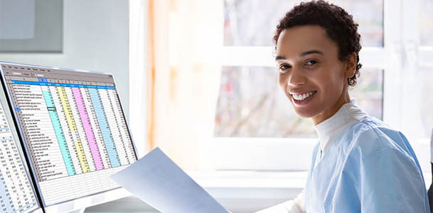 A physician uses a computer with two monitors to go over patient data